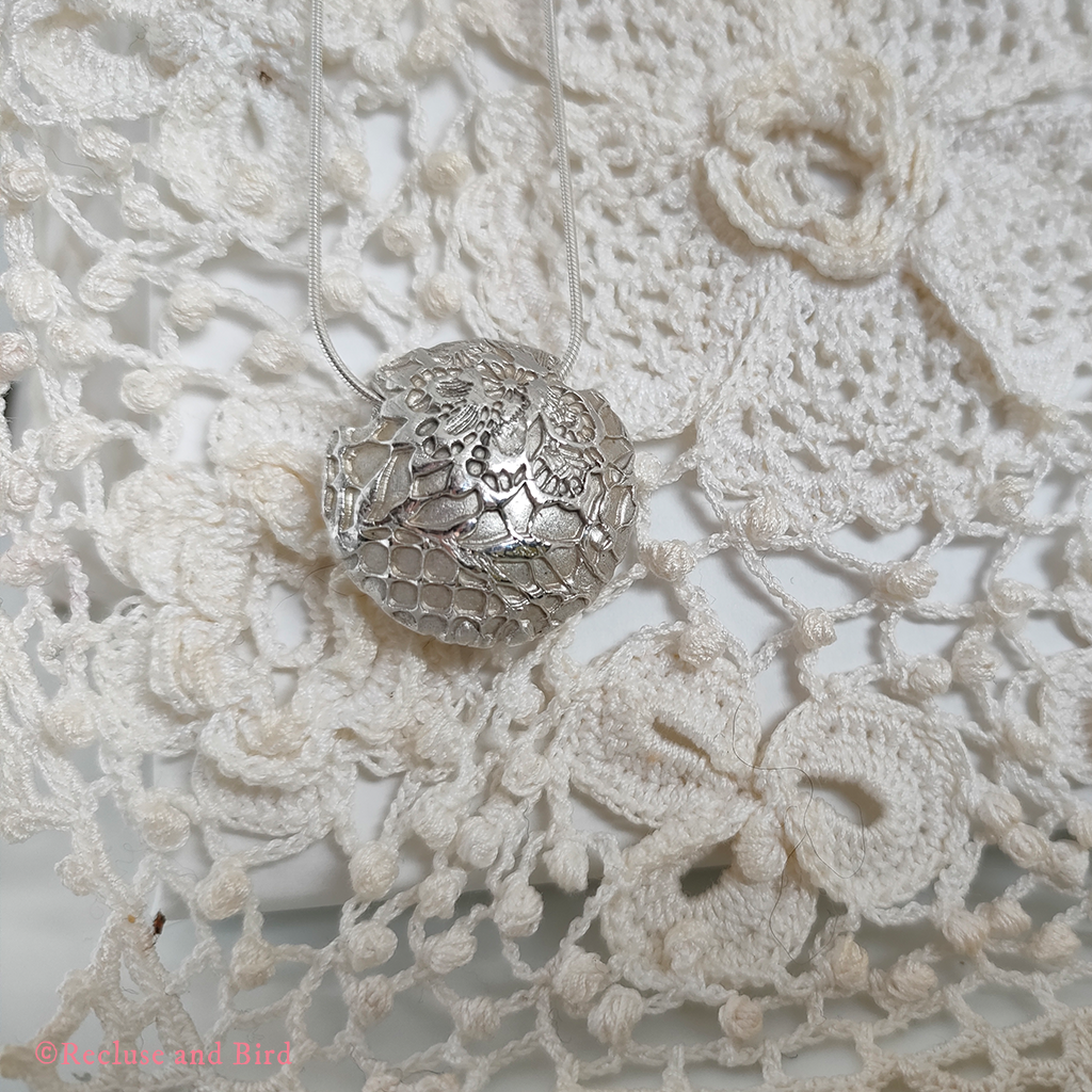 close up of a round lentil bead made of silver sitting on a traditio